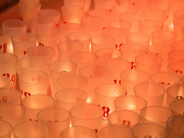 Warmes rötliches Licht von zahlreichen Teelichtern, die in durchscheinenden Bechern leuchten