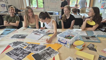 Schülerinnen und Schüler an einem großen Tisch mit historischen Bildern und Notizen