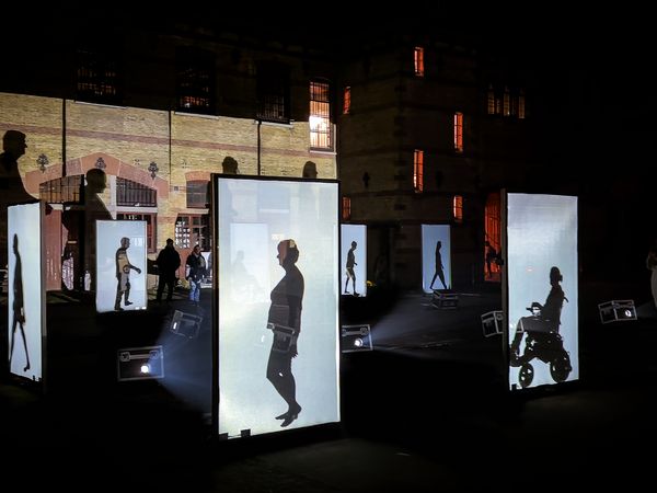 Große LED-Screens, auf denen die Umrisse und Schatten von Menschen in Bewegung zu sehen sind