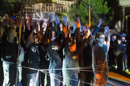 Junge Menschen auf einer Bühne, die Arme nach oben gestreckt
