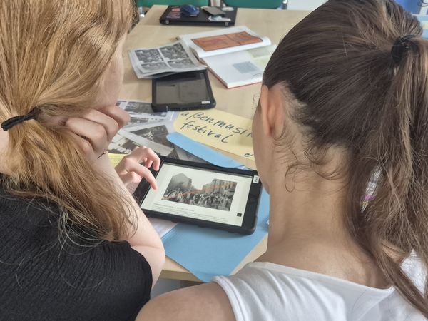Zwei junge Personen schauen sich Archivmaterial und alte Bilder an